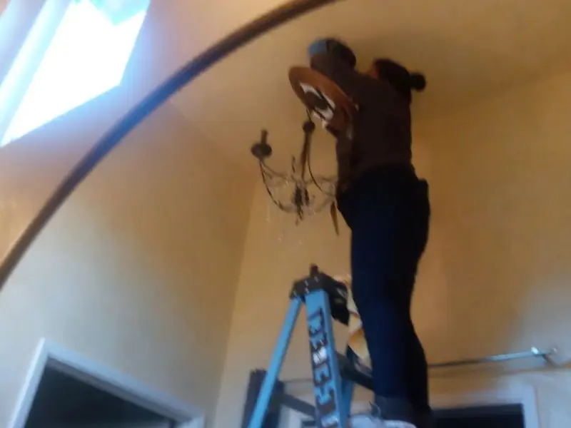 Electrician installing a chandelier in a Bergen residence
